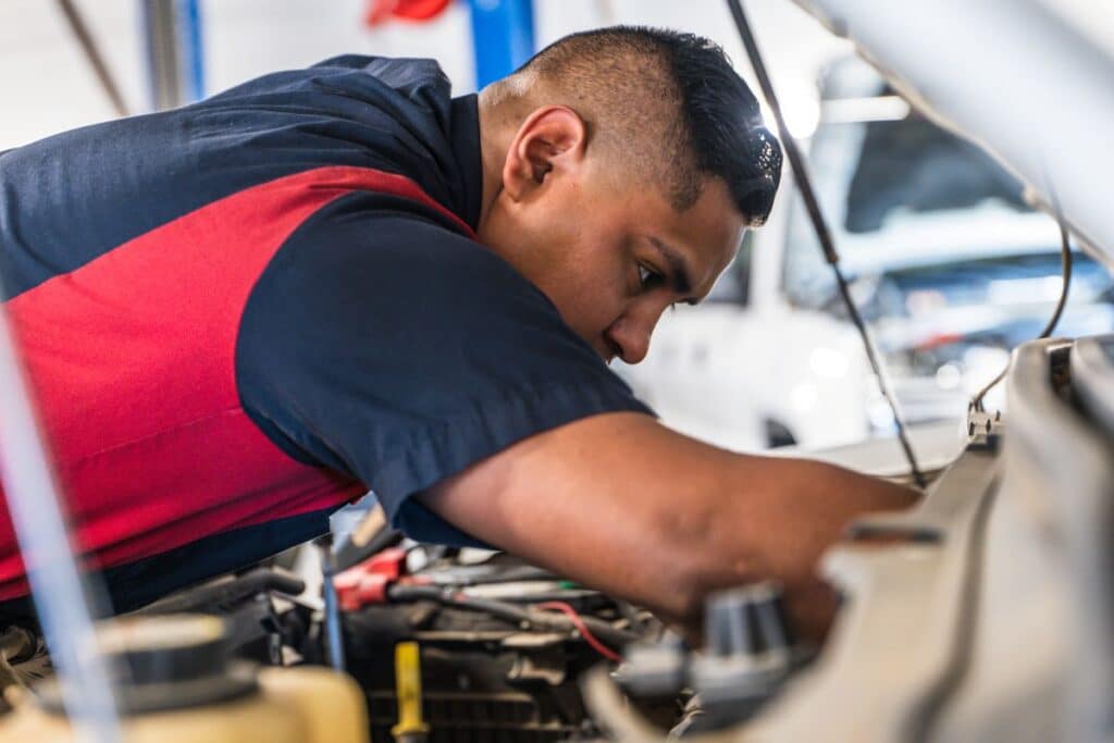 Technician working on vehicle in shop bay