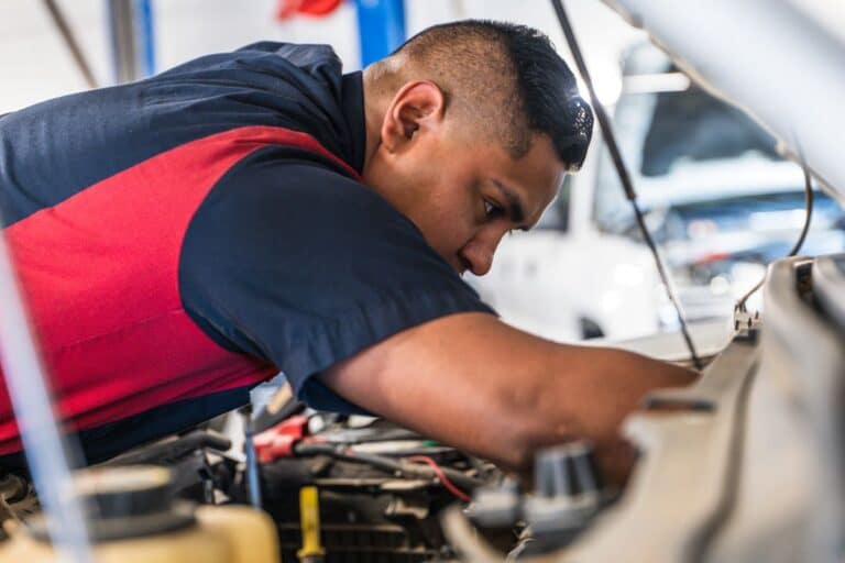 Technician working on vehicle in shop bay
