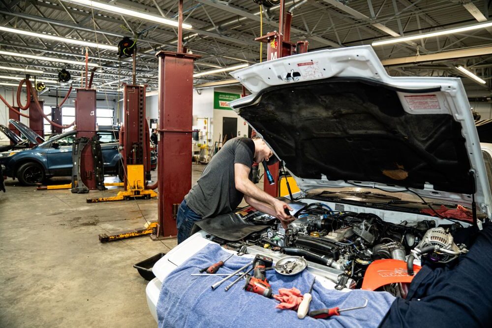 Technician working on vehicle with hood open